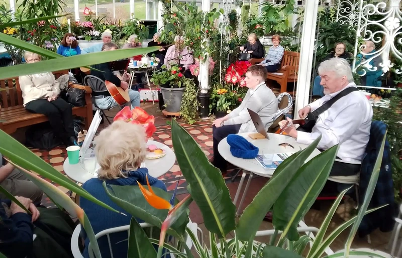 People sitting among Conservatory plants listening to music being played.